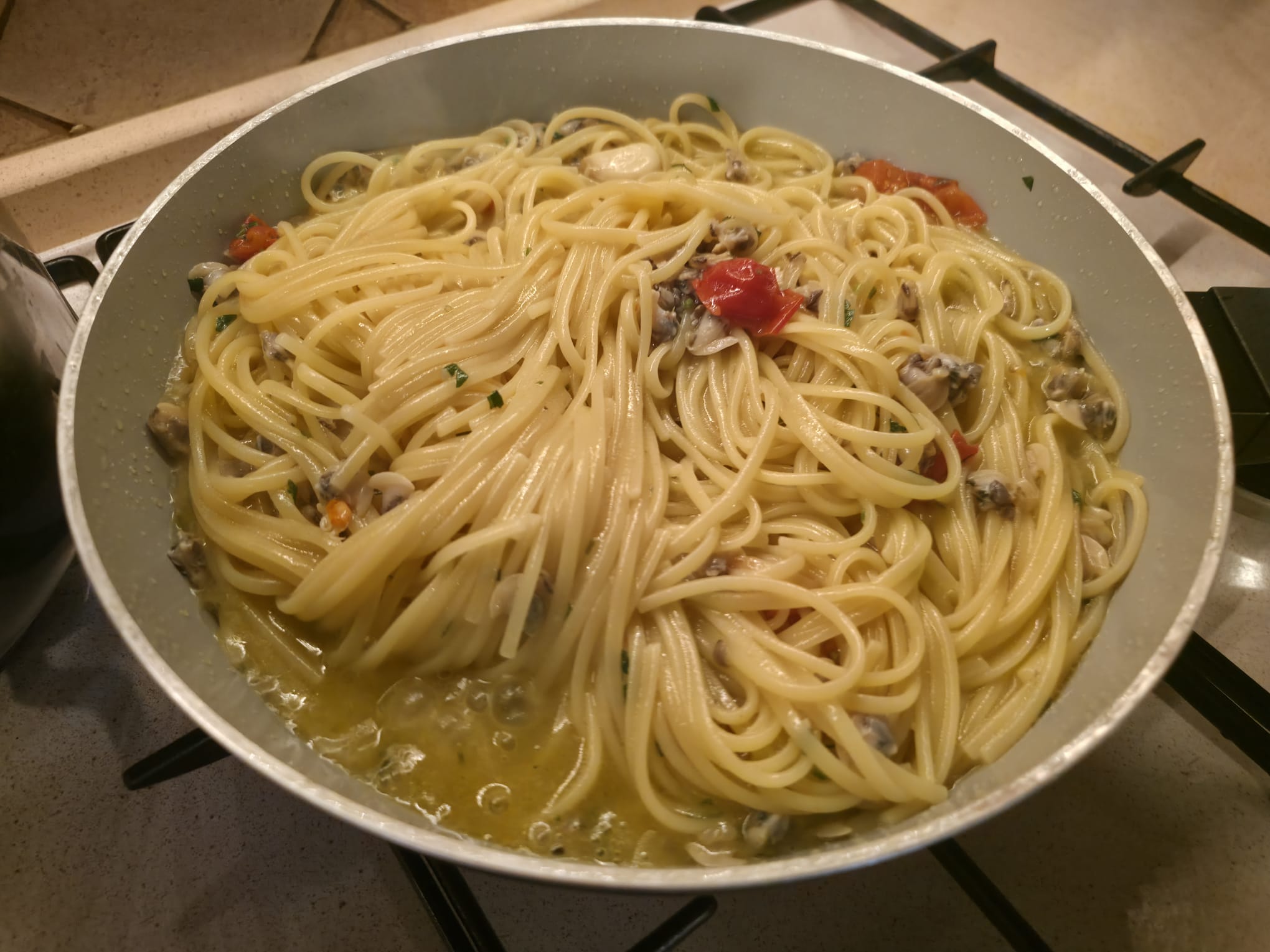 Linguine alle vongole in padella durante la mantecatura